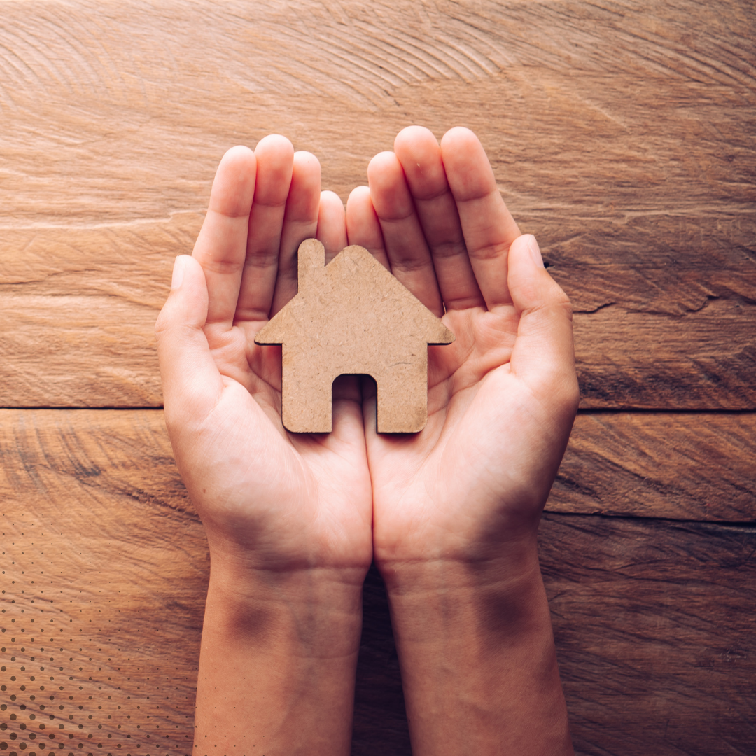 a person holding a small wooden house in their hands